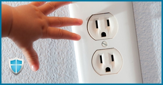 A toddler's hand reaching for an electrical outlet